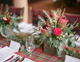 winter wedding centerpiece with red and green plaid table runner and red and green flowers in wooden square vase