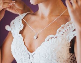 Bride putting on necklace