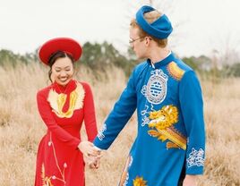 Couple walking in field wearing traditional Vietnamese ao dai