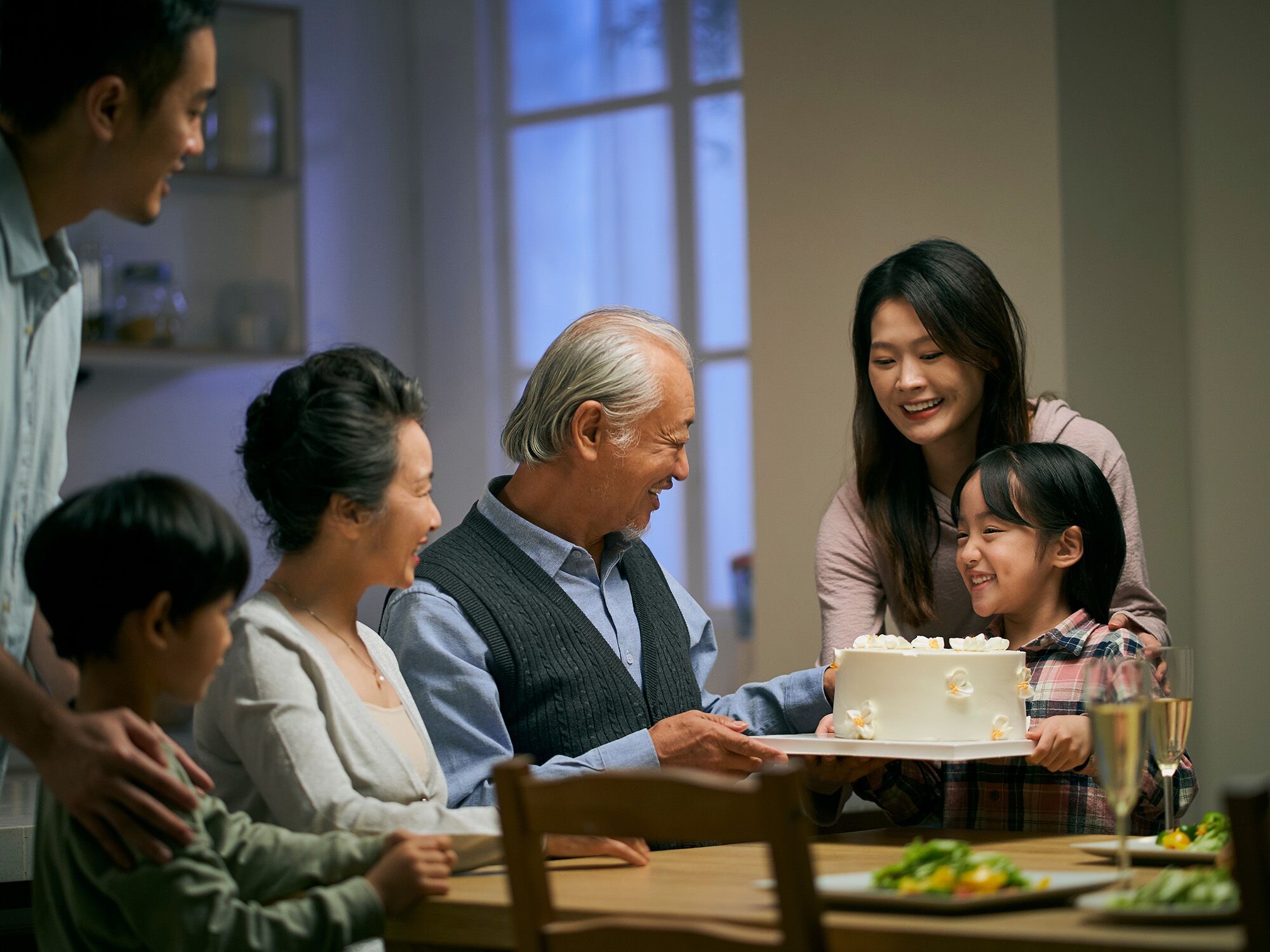 Family enjoying birthday cake around a dinner table