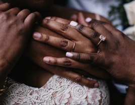 Couple holding hands with wedding rings on 