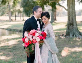 A couple pose together with a gorgeous red and white anemone bouquet.