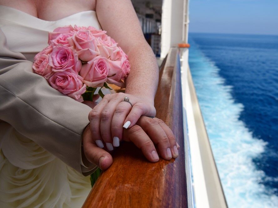Newlywed couple holding hands on a cruise