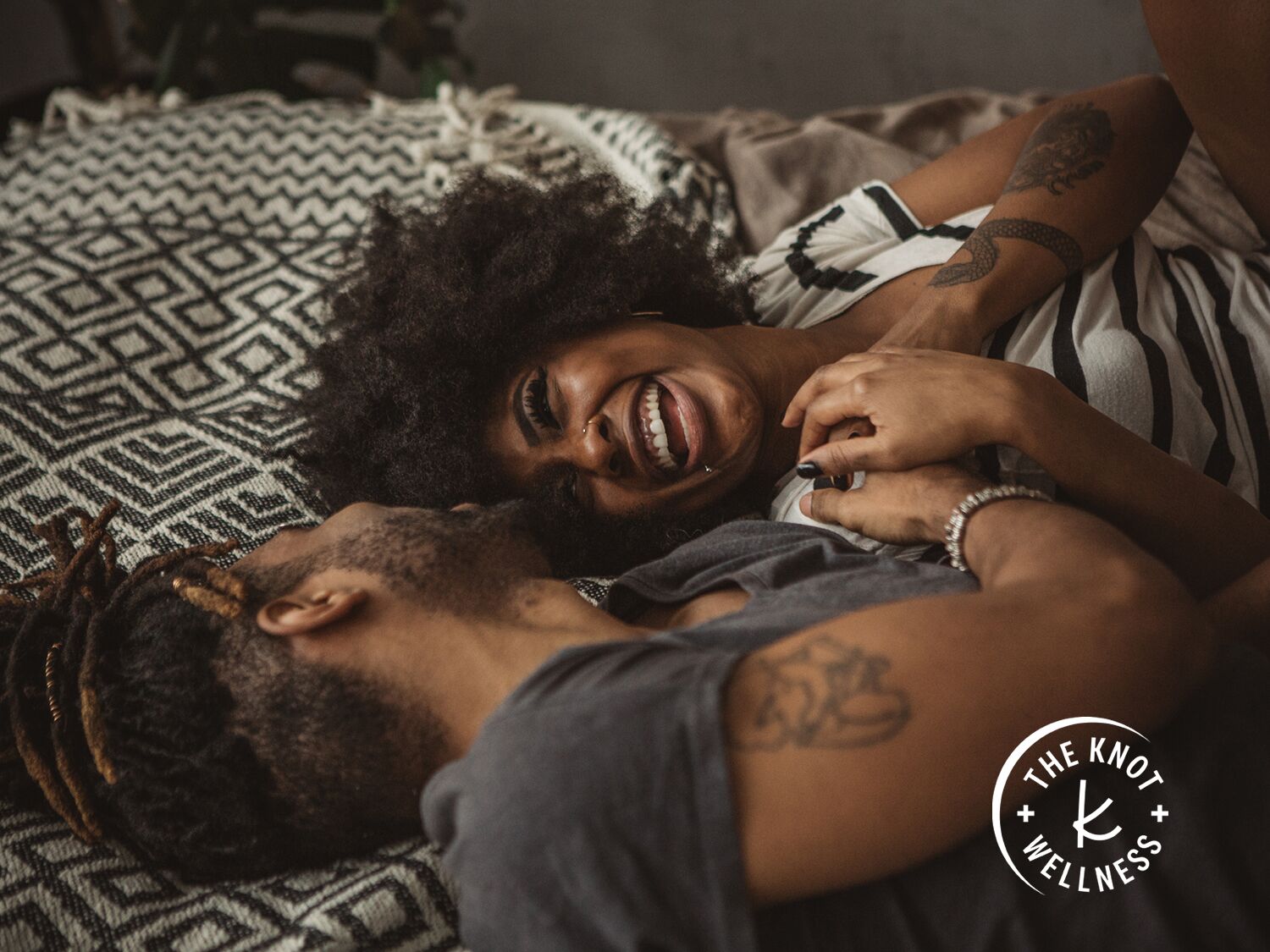 woman and man smiling together while lying on bed