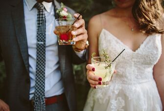Bride and groom hold colorful cocktails. 