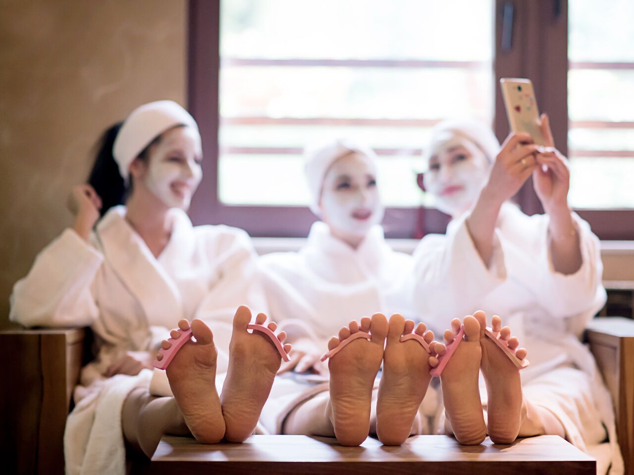 Three ladies getting facials and pedicures while taking a selfie