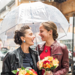 Brides on rainy wedding day under umbrella