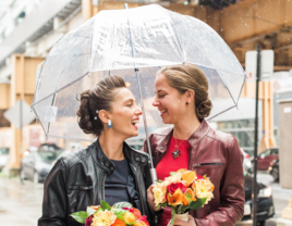 Brides on rainy wedding day under umbrella