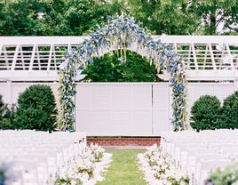 outdoor wedding ceremony venue wih arch of blue flowers at the altar