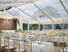 Inside clear tent reception space with hanging twinkling lights