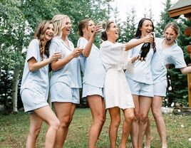 Bride popping champagne with her something blue crew