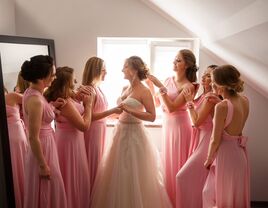 Bride surrounded with a group of bridesmaids who look at her adoringly. 