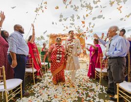 Guests throwing confetti as the couple walks down the aisle