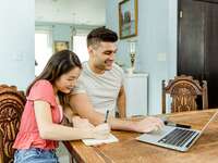 Engaged couple planning cash registry on laptop at home