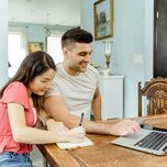 Engaged couple planning cash registry on laptop at home