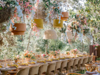 restaurant wedding venue with hanging pampas grass installation above long banquet table with orange velvet chairs