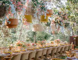 restaurant wedding venue with hanging pampas grass installation above long banquet table with orange velvet chairs