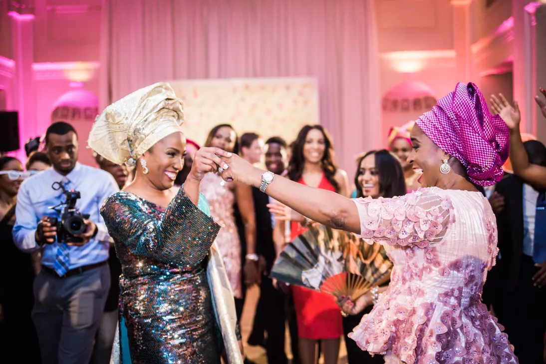 A bride and her wedding guest dance the night away in traditional Yoruba attire.