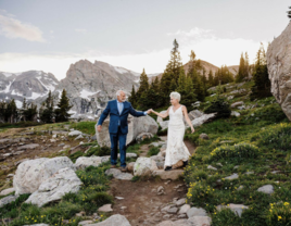 Older bride and groom walking through mountain side together