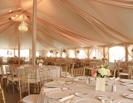 Inside grand marquee reception tent with hanging drapery and chandeliers