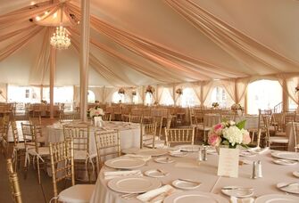 Inside grand marquee reception tent with hanging drapery and chandeliers