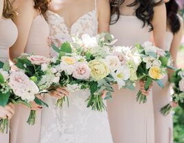 close up of bride and bridesmaids holding bouquets with pastel yellow peonies, light pink roses, queen annes lace and greenery