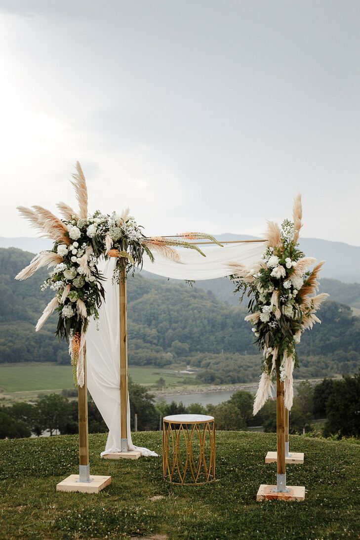 Chuppah on top of a hill with pampas grass decorations.