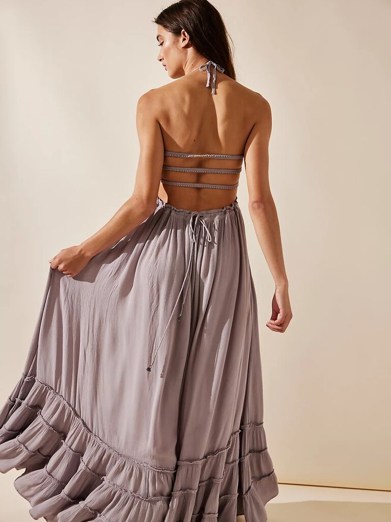 Model wears a gray maxi dress with an open back. 