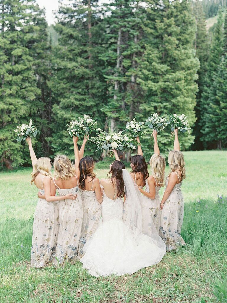 Photo of bridesmaids and bride holding bouquets in the air outside