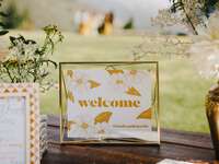 welcome sign with yellow and white floral print displayed on wedding gift table
