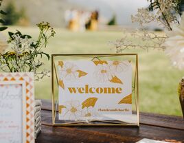 welcome sign with yellow and white floral print displayed on wedding gift table