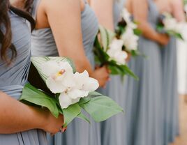 A wedding party lines up with their petite and beautiful white orchid bouquets.