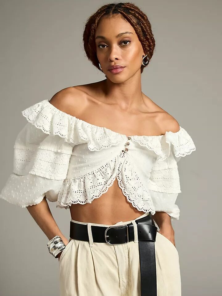 A white over-the-shoulder Victorian-style cropped blouse with three small floral buttons and mid-length puffy sleeves from Anthropologie