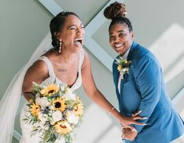 Couple laughing while posing with sunflower wedding arrangements