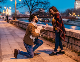 Man proposing to his girlfriend on sidewalk with dog