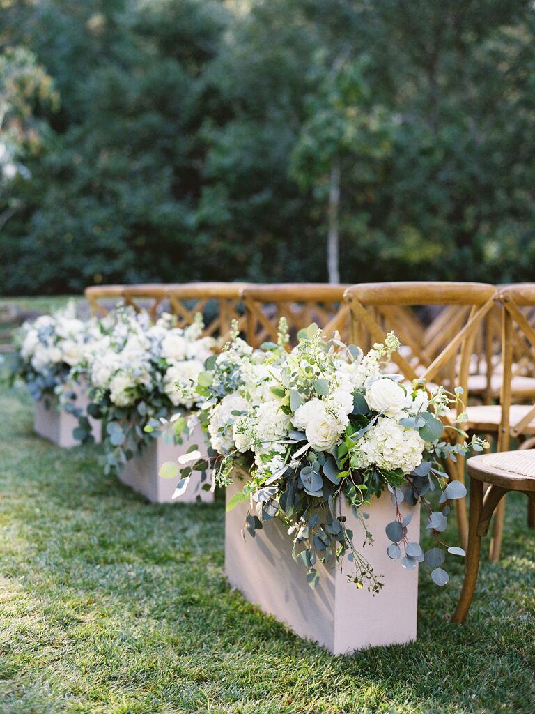 outdoor wedding ceremony aisle with white hydrangeas and eucalyptus in rectangular stone troughs