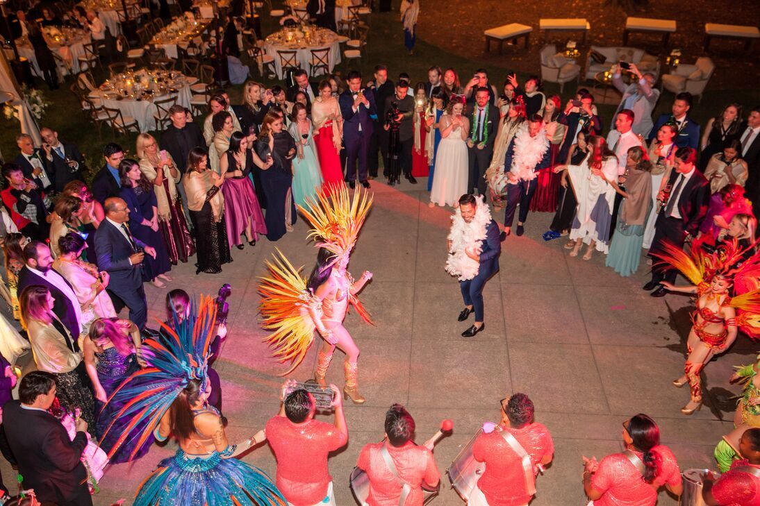 Weddings guests encircle the groom and a traditional dancer.