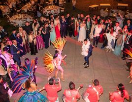 Weddings guests encircle the groom and a traditional dancer.