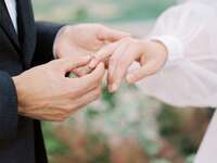 Groom putting ring on bride's finger