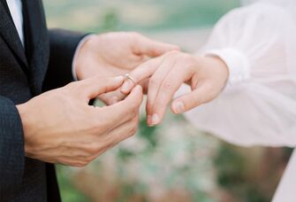 Groom putting ring on bride's finger