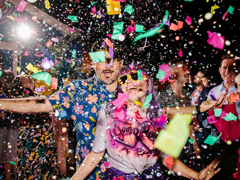 A wedding couple and guests on the dance floor with confetti