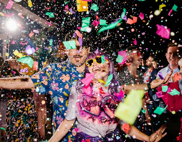 A wedding couple and guests on the dance floor with confetti
