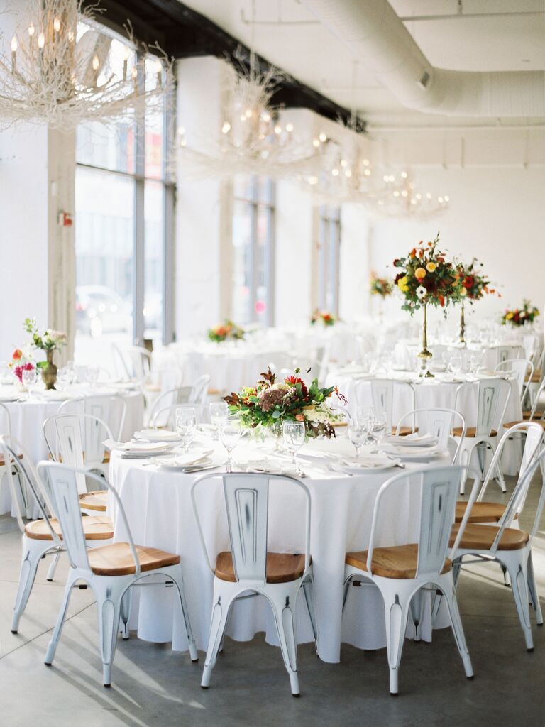 modern wedding reception space with round tables and white marais chairs