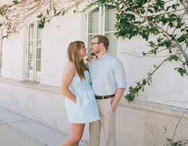 Couple standing outside of building posing and smiling at eachother