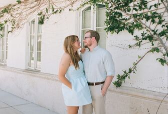 Couple standing outside of building posing and smiling at eachother