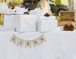 An assortment of wrapped gifts sits on a table at a wedding. 