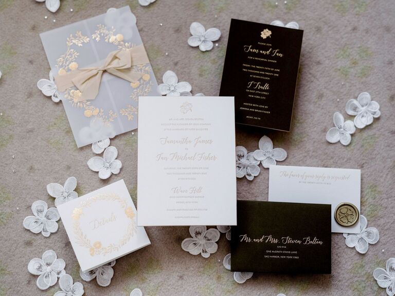 luxury wedding invitations embossed with gold calligraphy text against white background with black insert cards, vellum envelope and gold wax seal stamp