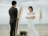 Bride reading unique wedding vows to groom while on the beach. 