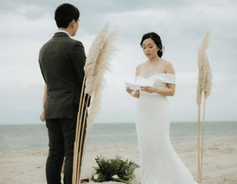Bride reading unique wedding vows to groom while on the beach. 