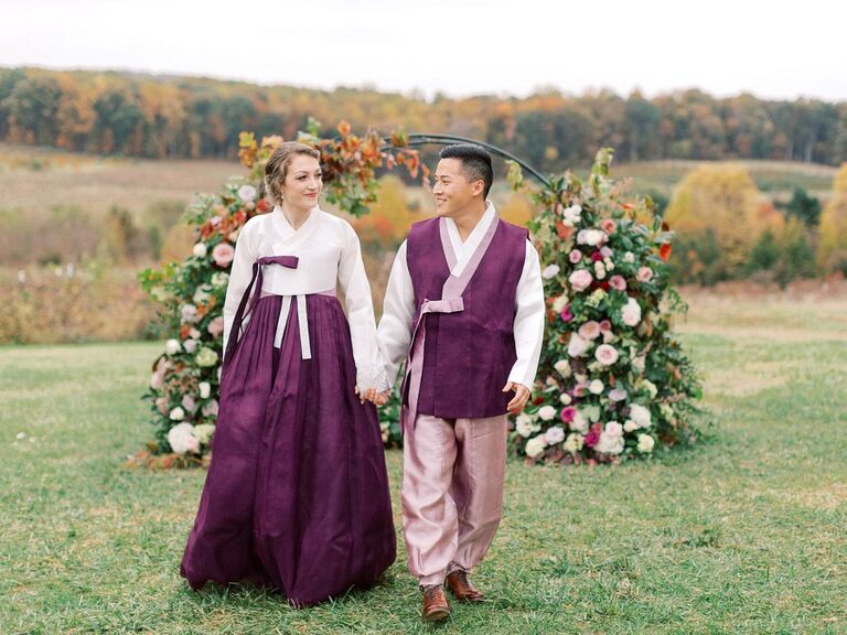 Couple in Korean hanboks holding hands during wedding portraits